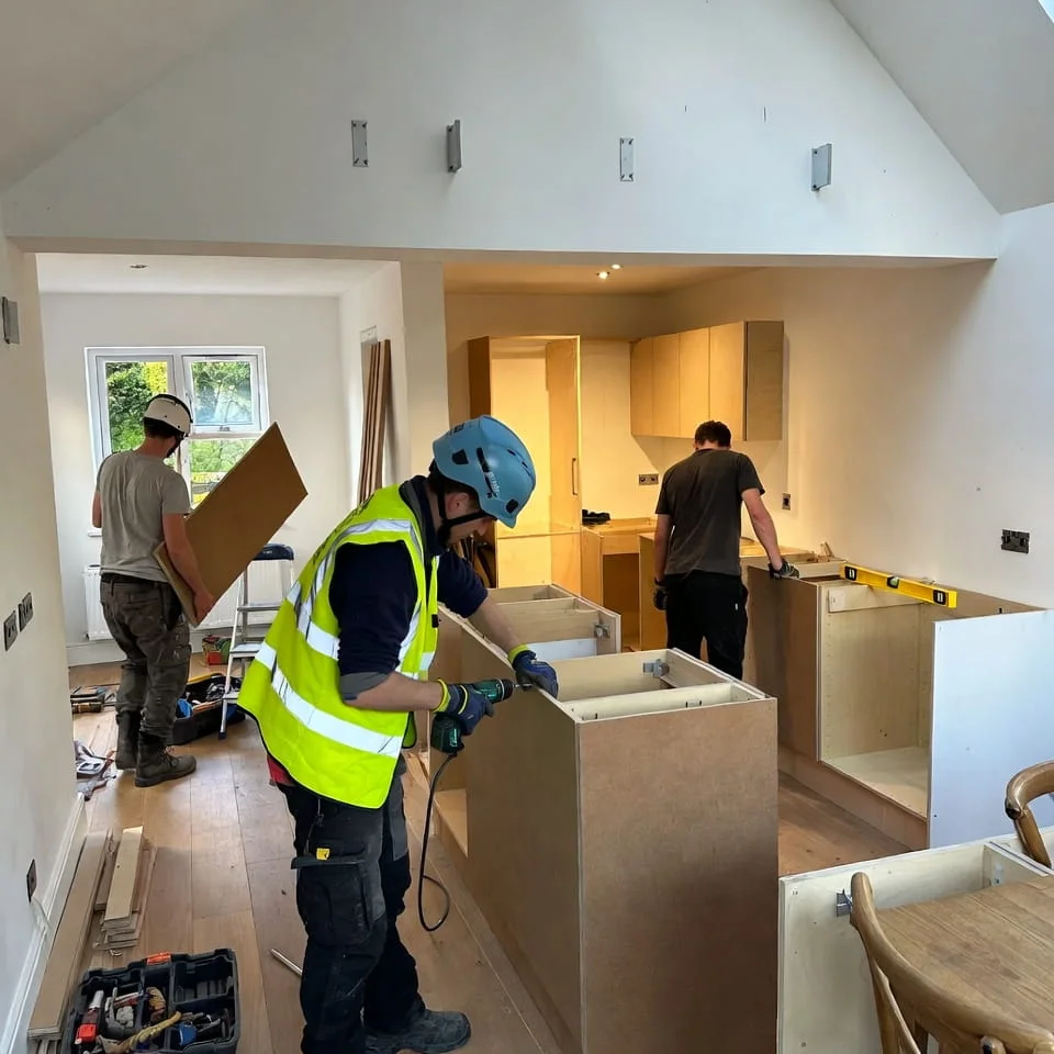 Builders installing kitchen cabinets during a full house renovation project in Berkshire