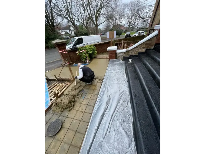 Contractor pouring concrete near front steps during driveway and landscaping project in Berkshire