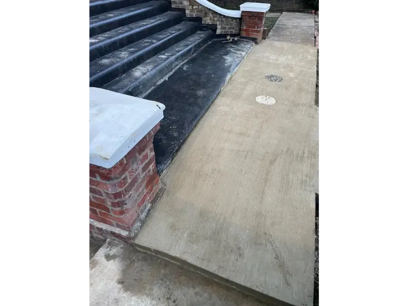 Freshly poured concrete pathway at residential front entrance with drainage covers in Berkshire